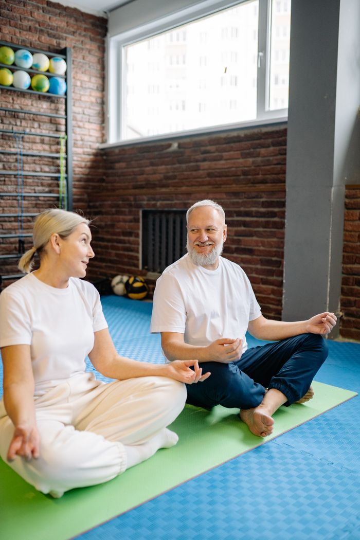 Elderly couple enjoying meditation and yoga together indoors, promoting wellness and fitness.